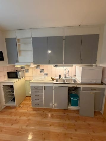 Kök före renovering med grå skåpluckor, rosa kakel och diskbänk. Kök före renovering med grå skåpluckor, rosa kakel och diskbänk.