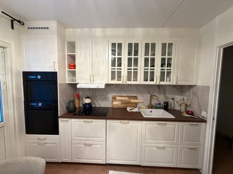 Färdigt kök med vita skåpluckor, vitrinskåp, mörk bänkskiva och vit diskho. Färdigt kök med vita skåpluckor, vitrinskåp, mörk bänkskiva och vit diskho.